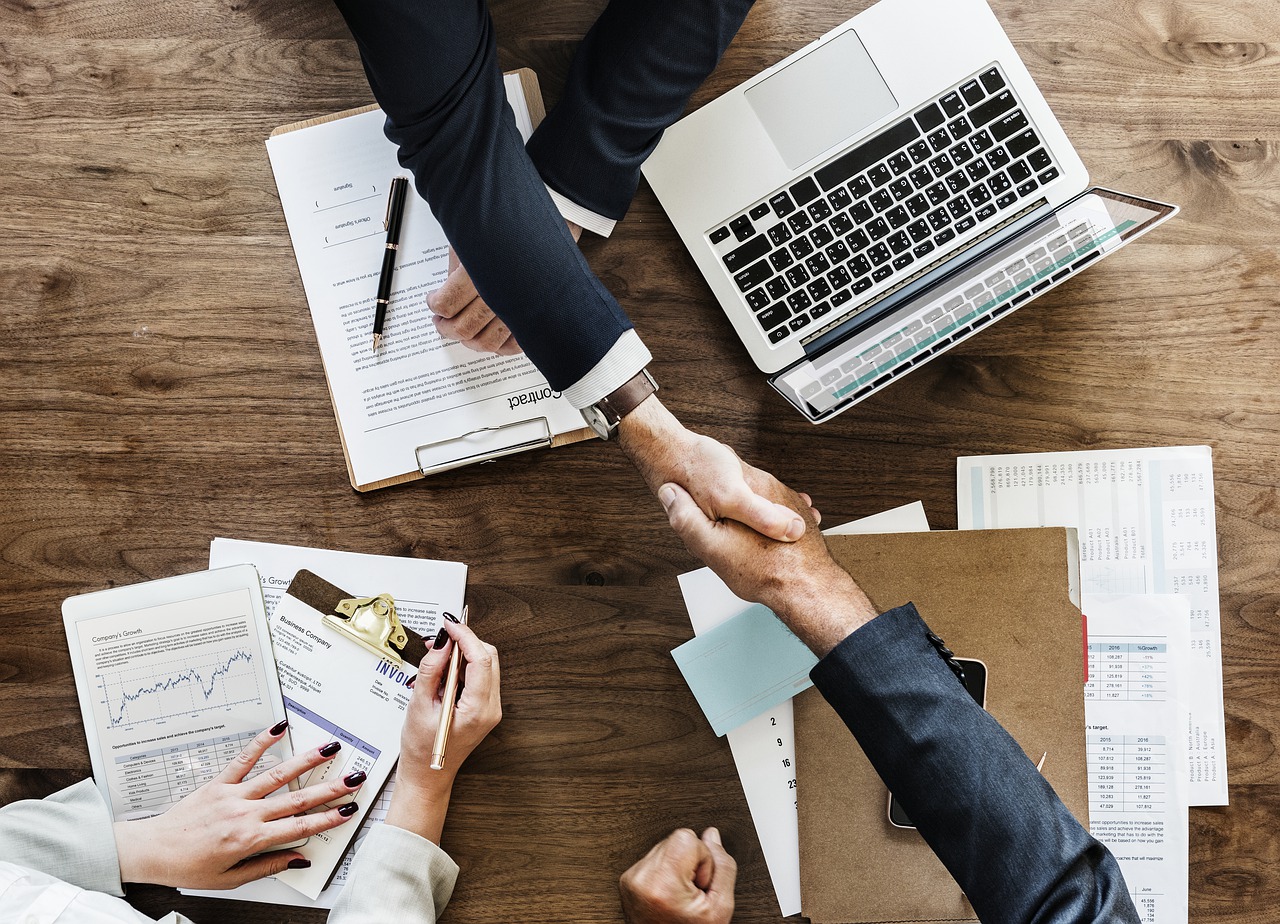 two business people shaking hands with laptop